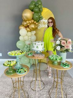 a woman standing in front of a table filled with cakes and cupcakes on top of small tables