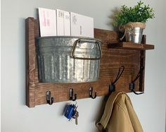 a metal bucket and some keys on a wooden shelf next to a potted plant