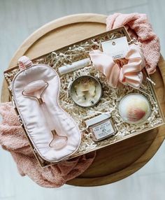 an open box with various items in it on top of a wooden table next to a pink towel