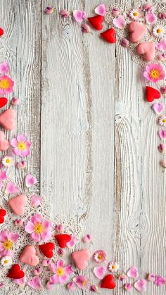 some pink flowers and hearts on a white wooden surface