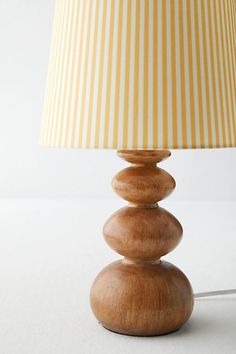 a lamp that is sitting on top of a white surface with a yellow and white striped lampshade