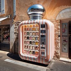 a pink vending machine sitting on the side of a road next to a building