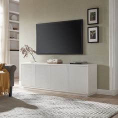 a large flat screen tv mounted to the side of a white cabinet in a living room