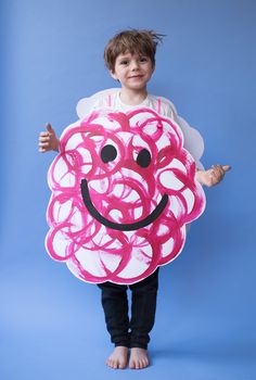 a young boy holding a paper plate with a smiling face on it's side