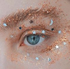 a woman's eye with gold glitter and stars on her eyes, as if it were in the sky