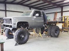 a large gray truck parked inside of a garage next to a workbench filled with tools