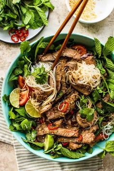 a blue bowl filled with meat and veggies on top of a white table