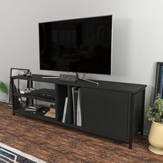 a flat screen tv sitting on top of a black entertainment center next to a potted plant