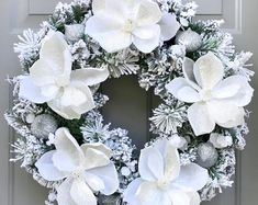 a wreath with white flowers and silver ornaments