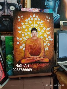 there is a buddha painting on the wall next to a laptop computer and other art work