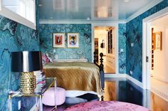 a bedroom with blue wallpaper and gold bedding