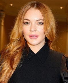 a woman with long red hair is wearing a black dress and posing for the camera