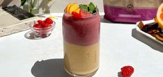 a smoothie is sitting on a table next to some fruit and other food items