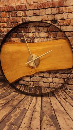 a clock made out of wood sitting on top of a wooden floor next to a brick wall