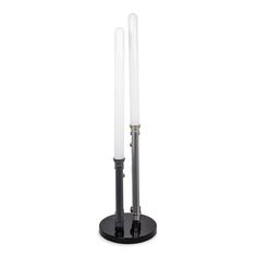 two white candles sitting on top of a black stand