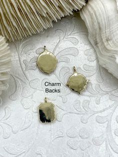 three charms that have been placed on top of a white fabric with the words charm backs