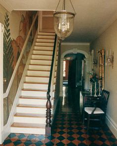 the hallway is decorated with black and white checkered flooring, an ornate chandelier, and a painting on the wall