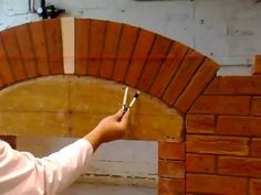 a brick oven being worked on by a man with paintbrushes in his hand