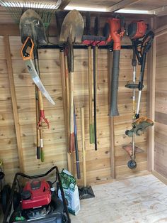 there are many tools hanging on the wall in this garage with wood paneled walls