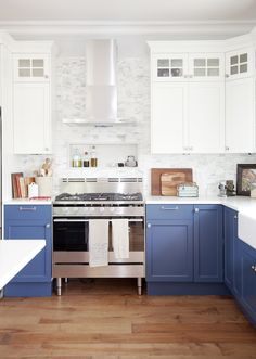 a kitchen with blue and white cabinets, stainless steel appliances and wood flooring is shown