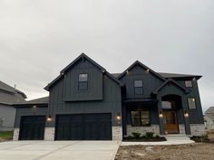 a gray house with two garages and lights on the front door is pictured in this image