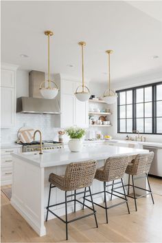 a kitchen with white counter tops and stools in front of an island that has four chairs