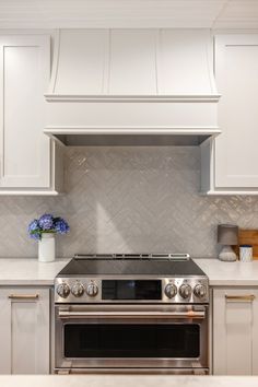 a stove top oven sitting inside of a kitchen next to white cabinets and counter tops