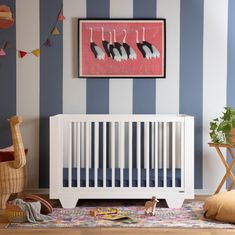 a baby's room with blue and white stripes on the walls, a crib in the foreground