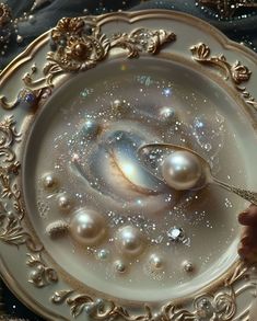 a plate with pearls on it and a spoon in the middle that is being held by someone's hand