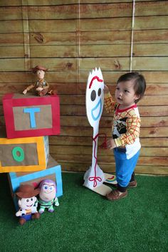 a little boy standing next to some toys