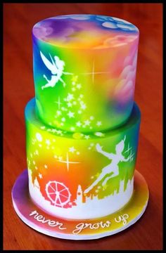 two tiered cake decorated with colorful icing and tinker on wooden table top