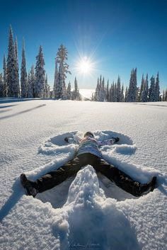 a person laying in the snow with their legs spread out to look at the sun