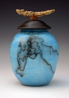 a small blue vase with a map on it's lid and a gold chain hanging from the top