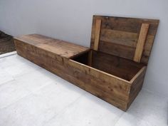 an empty wooden box sitting on top of a white floor next to a planter