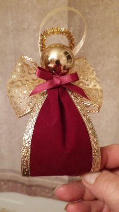 a hand holding an ornament with a bow on it