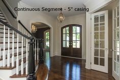 an entryway with wooden floors and white walls, two doors leading to another room