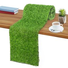 a table that has some grass on it and a cup of coffee next to it