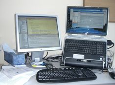 two laptop computers sitting on top of a desk next to a desktop computer monitor and keyboard