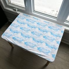 a table with a blue and white cloud design on it in front of a window