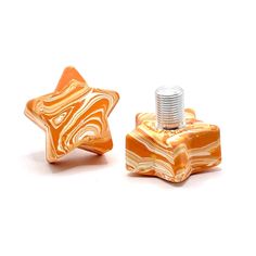 two orange and white marbled objects on a white surface, one has a screw in the middle