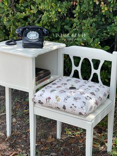 an old fashioned telephone sits next to a small white desk with a pillow on it