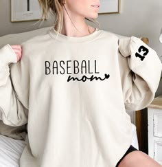 a woman wearing a sweatshirt that says baseball mom on it and has her hands behind her back