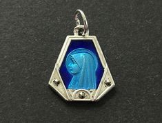 A nice vintage French Lourdes two toned blue enamel pendant/charm.  The base is a silver plate with a center two toned Lourdes with Marcasite bead accents.  Beautiful style.  Vintage catholic blue enamel medal.  Nice piece to add to your collection. It measures 1/2" tall x 1/2" wide In very good condition for its age.   Please visit our shop to view our entire vintage selection at OldSaltyShed: https://www.etsy.com/shop/OldSaltyShed?ref=hdr_shop_menu Thank you for shopping at OldSaltyShed! **Please Note:  All International orders do not include Custom Fee's, VAT Fee's or any other Fee/Tax your particular country requires. Vintage Blue Enamel Necklace, Blue Engraved Enamel Jewelry, Blue Enamel Engraved Jewelry, Blue Hallmarked Medallion Jewelry, Collectible Blue Engraved Necklace, Blue Engraved Necklace Collectible, Blue Engraved Enamel Necklaces, Blue Enamel Engraved Necklace, Vintage Charm Blue Jewelry For Jewelry Making