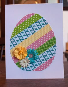 a card with an easter egg and flowers on it, sitting on a wooden table