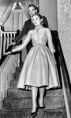 an old black and white photo of a woman walking down the stairs with her man