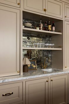 a kitchen with white cabinets and marble counter tops, gold pulls on the cabinet doors