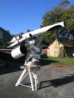 a telescope sitting on top of a tripod in the middle of a driveway next to a house