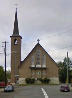 an old church with a steeple on the side and cars parked at the curb