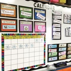 a bulletin board with calendars on it in front of a classroom wall filled with magnets