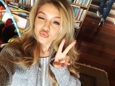 a young woman making the peace sign with her fingers while standing in front of a bookshelf